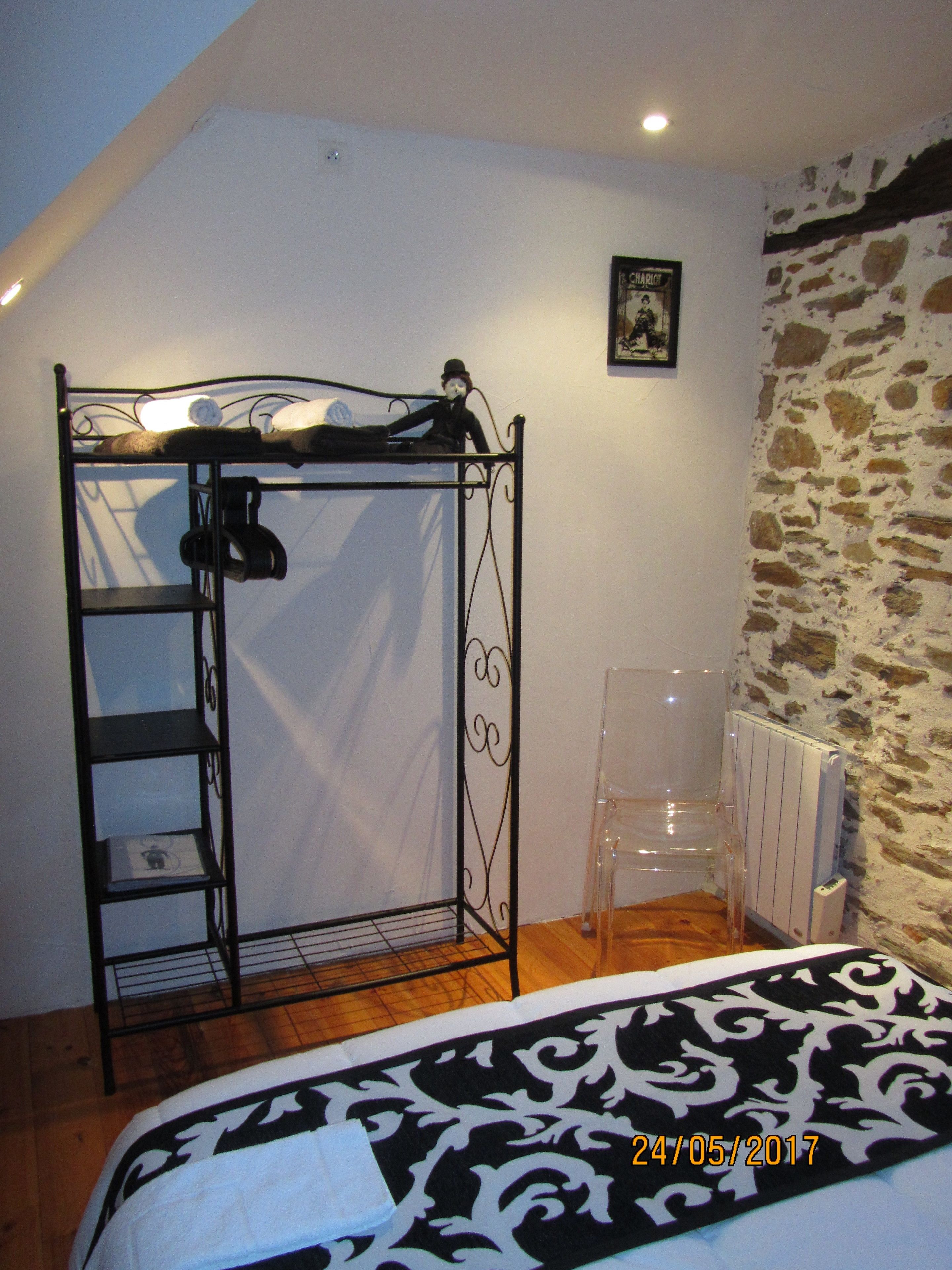 Un dormitorio con una cama litera, un radiador, una silla de plástico transparente y una colcha estampada.