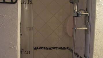 A shower area with a showerhead, a handheld shower attachment, and a shower curtain with text.