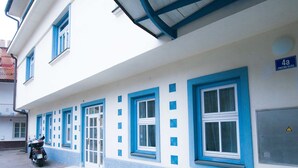 A building with a blue and white facade, a motorbike parked in front, and a sign indicating room number 4a.
