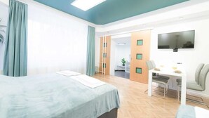 A modern hotel room with a bed, a desk, and a TV.