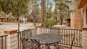 An outdoor patio with a round metal table and chairs, surrounded by a brick wall and metal railing. - Popko's Place #1426 (Big Bear Lake)
