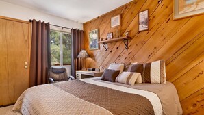 A bedroom with a large bed, a desk, a chair, and a window with curtains. - Popko's Place #1426 (Big Bear Lake)