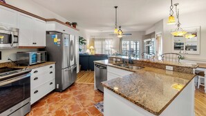 A modern kitchen with granite countertops, stainless steel appliances, and pendant lighting. - T's Retreat: Semi-oceanfront, third floor condo, two beach accesses close by. (Kill Devil Hills)