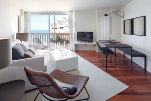 A modern living room with a sofa, a dining table, and a TV. - UNBEATABLE SEAFRONT BRAND NEW APARTMENT (Zarautz)