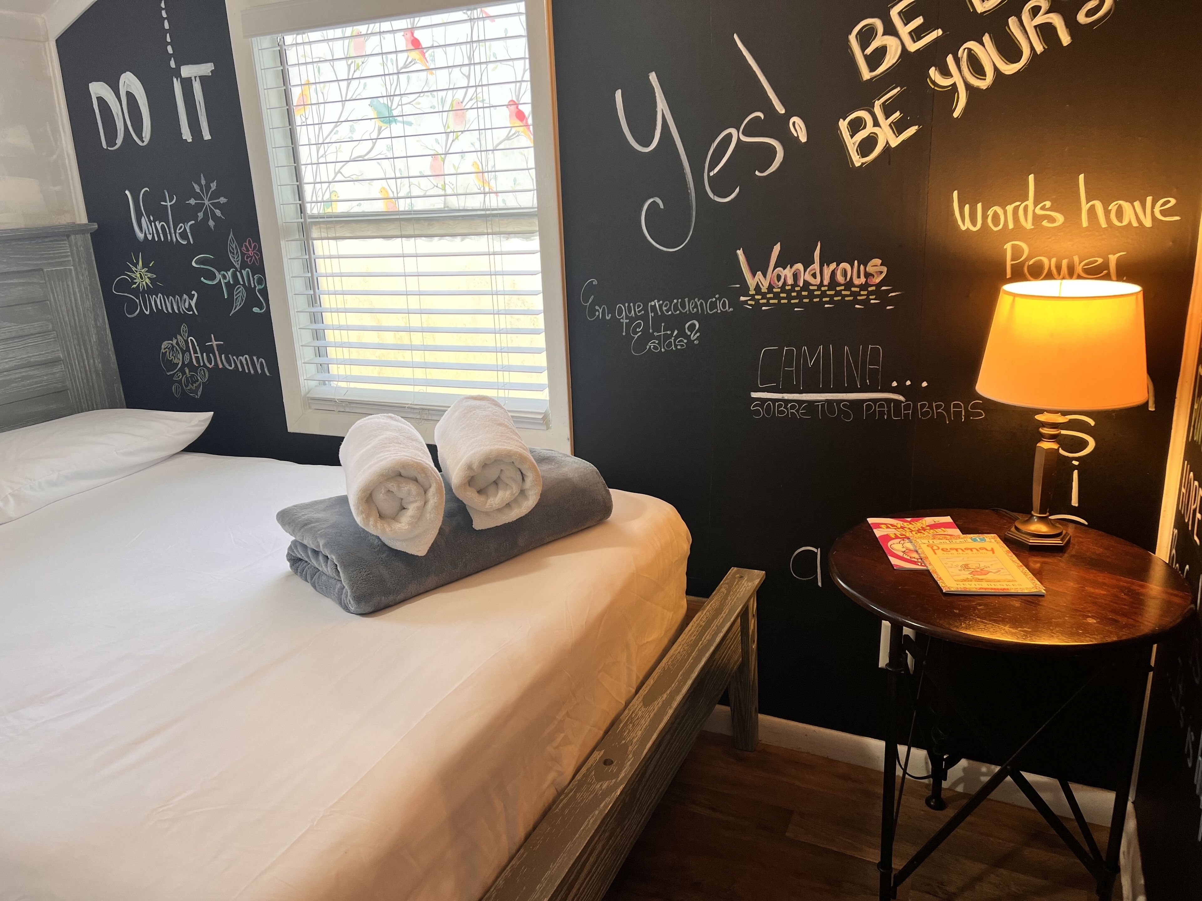 Une chambre d’hôtel équipée d’un lit, de serviettes, d’une table de chevet avec une lampe et d’œuvres d’art murales inspirantes.