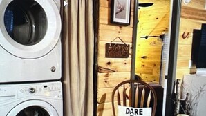 Un espace buanderie comprenant un lave-linge, une chaise ornée d’une citation inspirante et un mur en bois décoré dans le style d’une grange.
