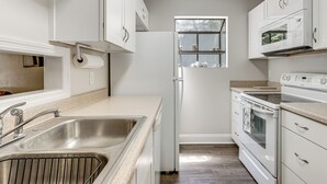 A kitchen with white cabinets, a stainless steel sink, a built-in oven, and a microwave. - Charming Tallahassee Townhouse ~ 3 Mi to FSU! (Tallahassee)