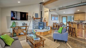 A modern living room with a stone fireplace, wooden furniture, and a television. - 'Coastal Soul' Arcata Area California Home (Blue Lake)