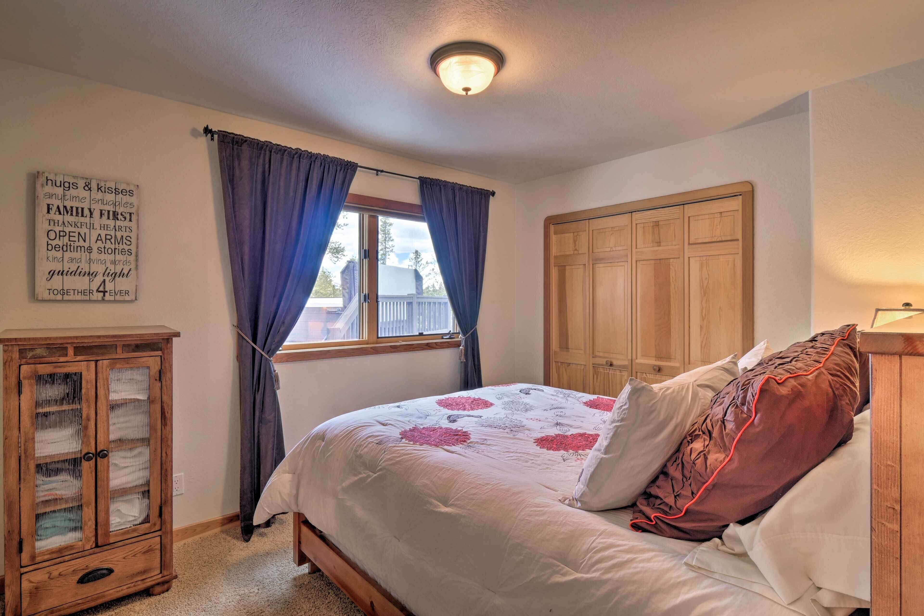 Un dormitorio con cama, armario de madera, aparador y ventana con cortinas.