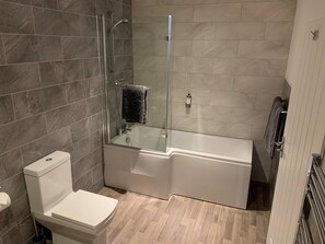Un baño con ducha de vidrio, inodoro blanco y bañera.