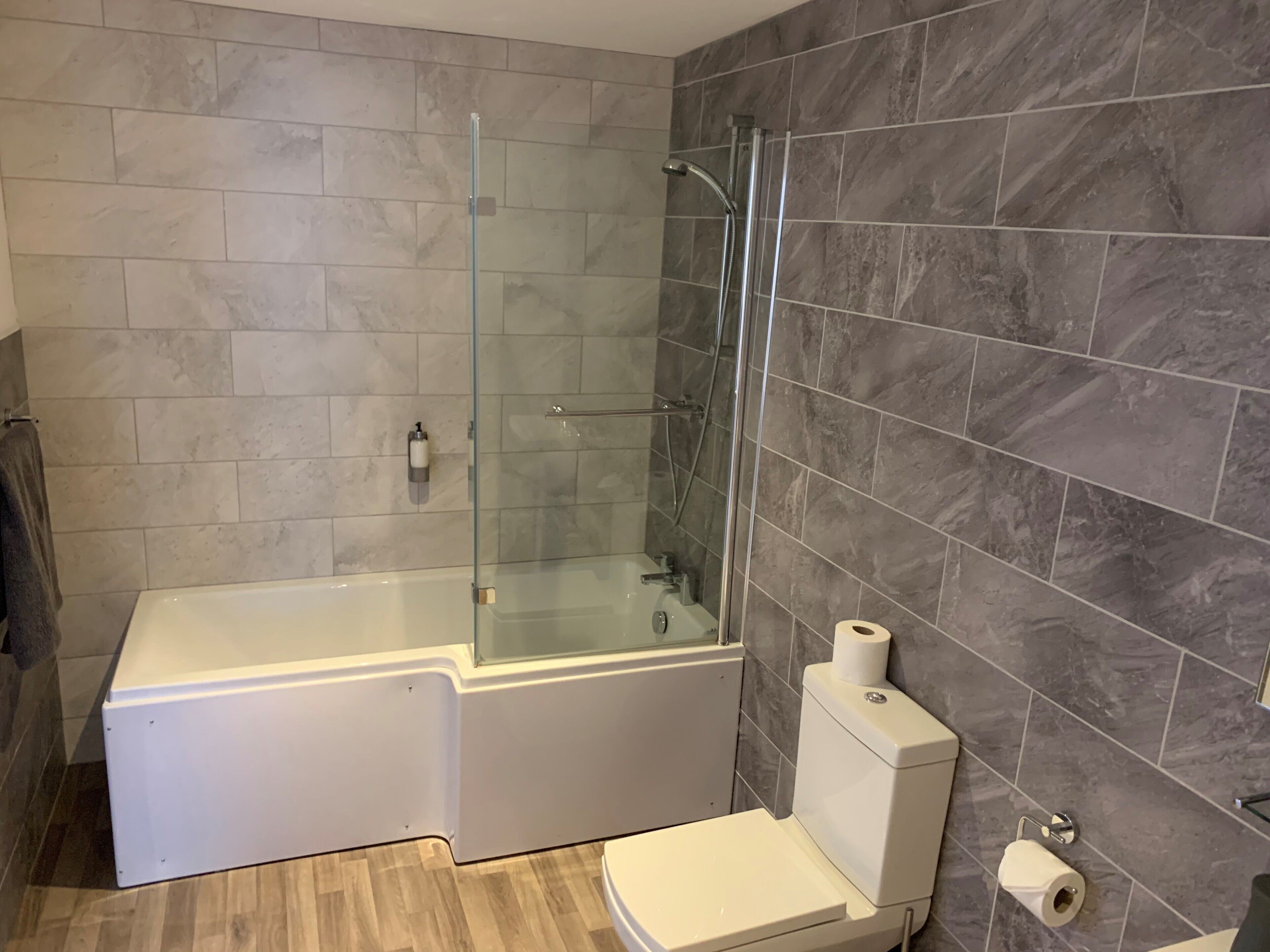Un baño con ducha envuelta en vidrio, una bañera blanca y un inodoro.