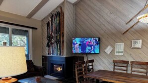 Un accogliente soggiorno con camino, una televisione montata a parete e un'area pranzo con mobili in legno.