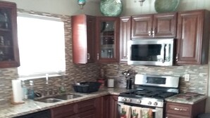A kitchen with wooden cabinets, a stainless steel stove, a microwave, and a dishwasher. - Entertainment 4539 (Snellville)
