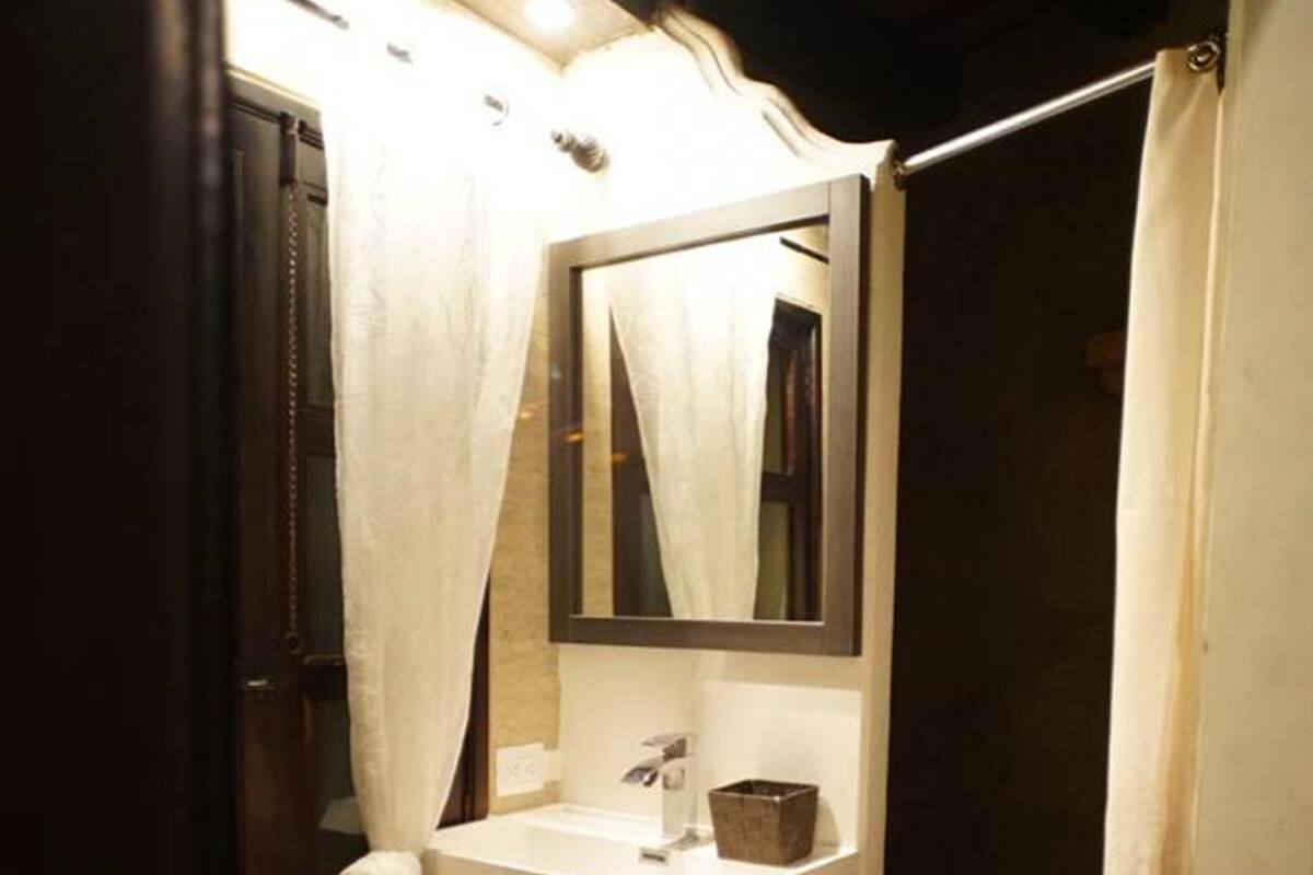 Een badkamer met een witte wastafel, een spiegel en een douchegordijn.