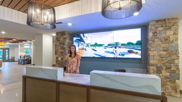 A reception area with a stone wall, a large TV screen displaying a scenic view, and wooden paneling on the ceiling.