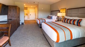 A hotel room with two beds, a desk, and a chair.
