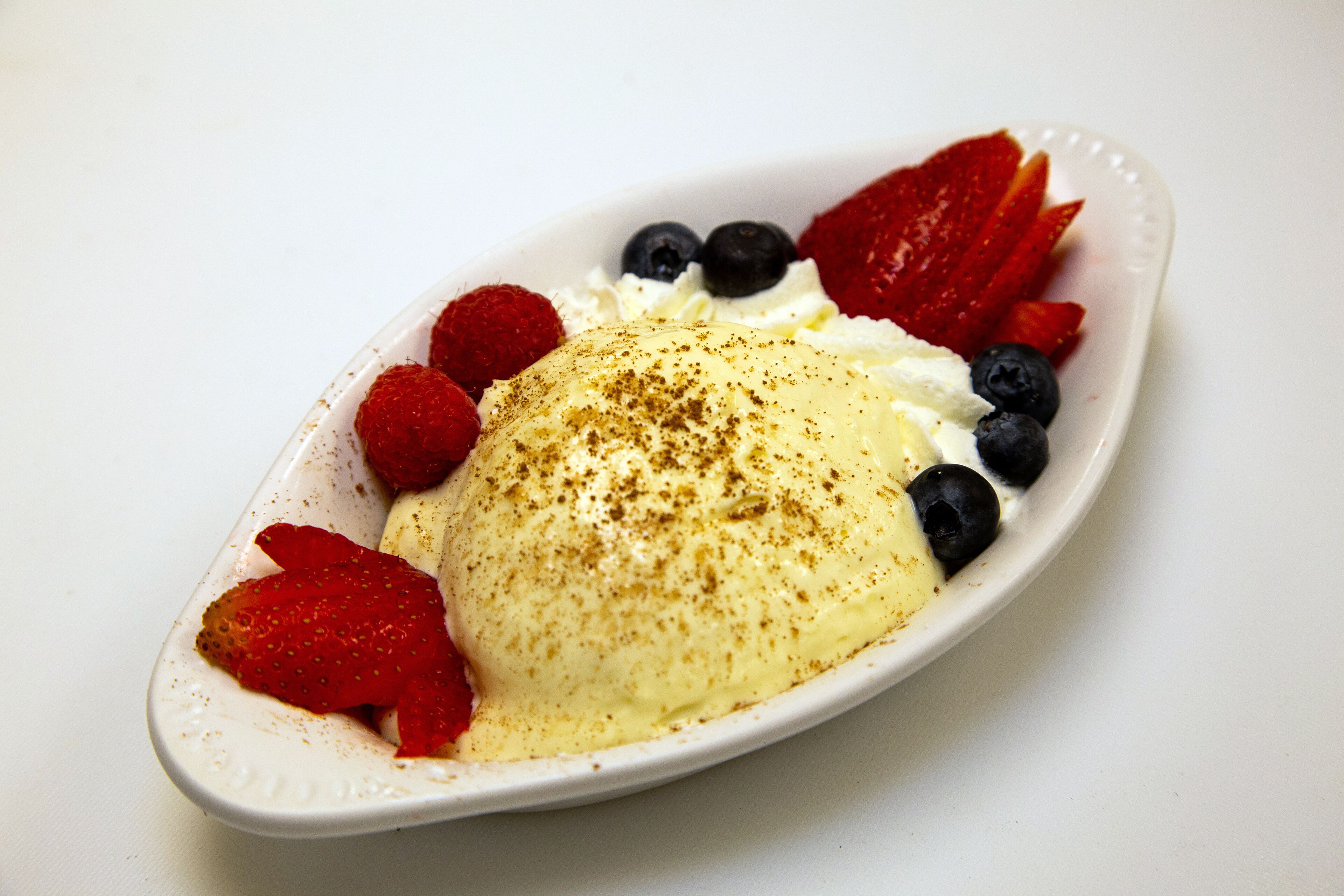 A dessert with strawberries, blueberries, and raspberries on a white plate.