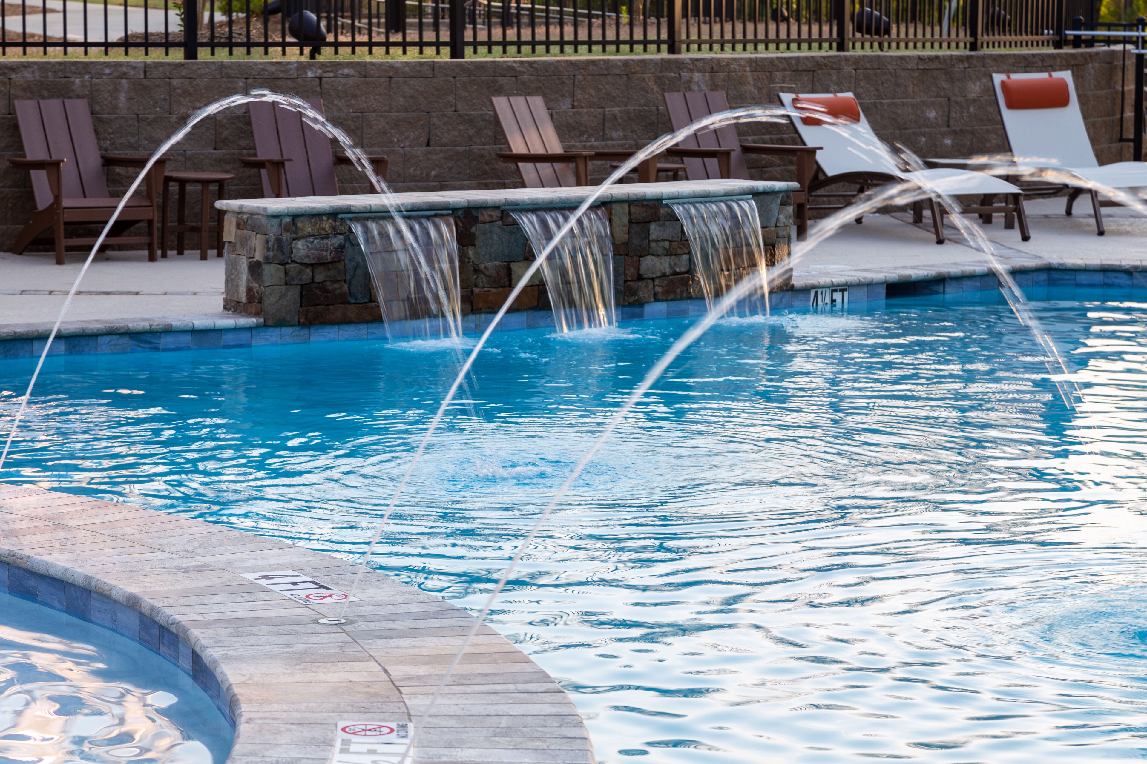Een zwembad met diverse waterattracties, waaronder een waterval en een jacuzzi.