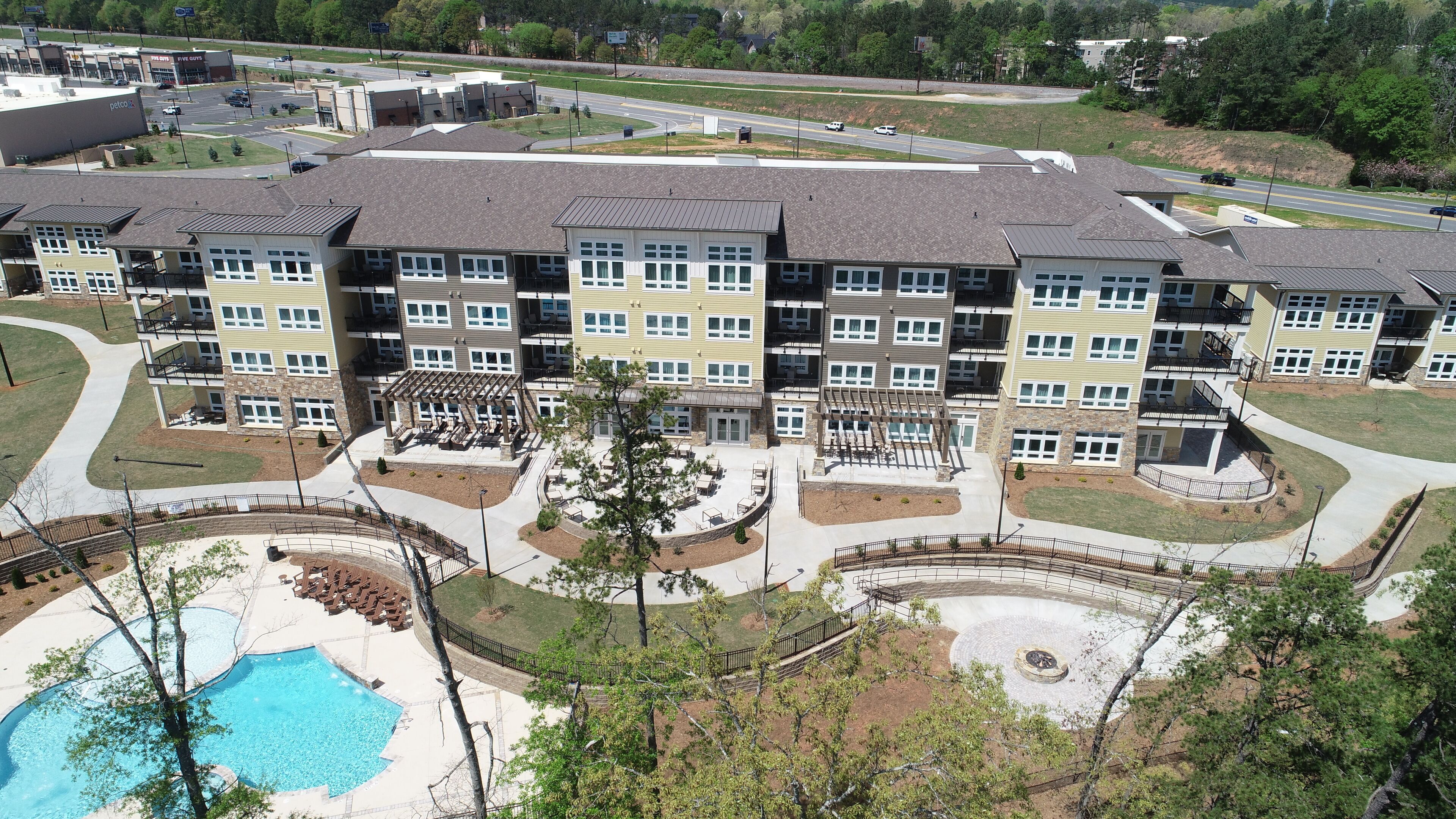 Un edificio residencial de varios pisos con un patio central, piscina y zona ajardinada.