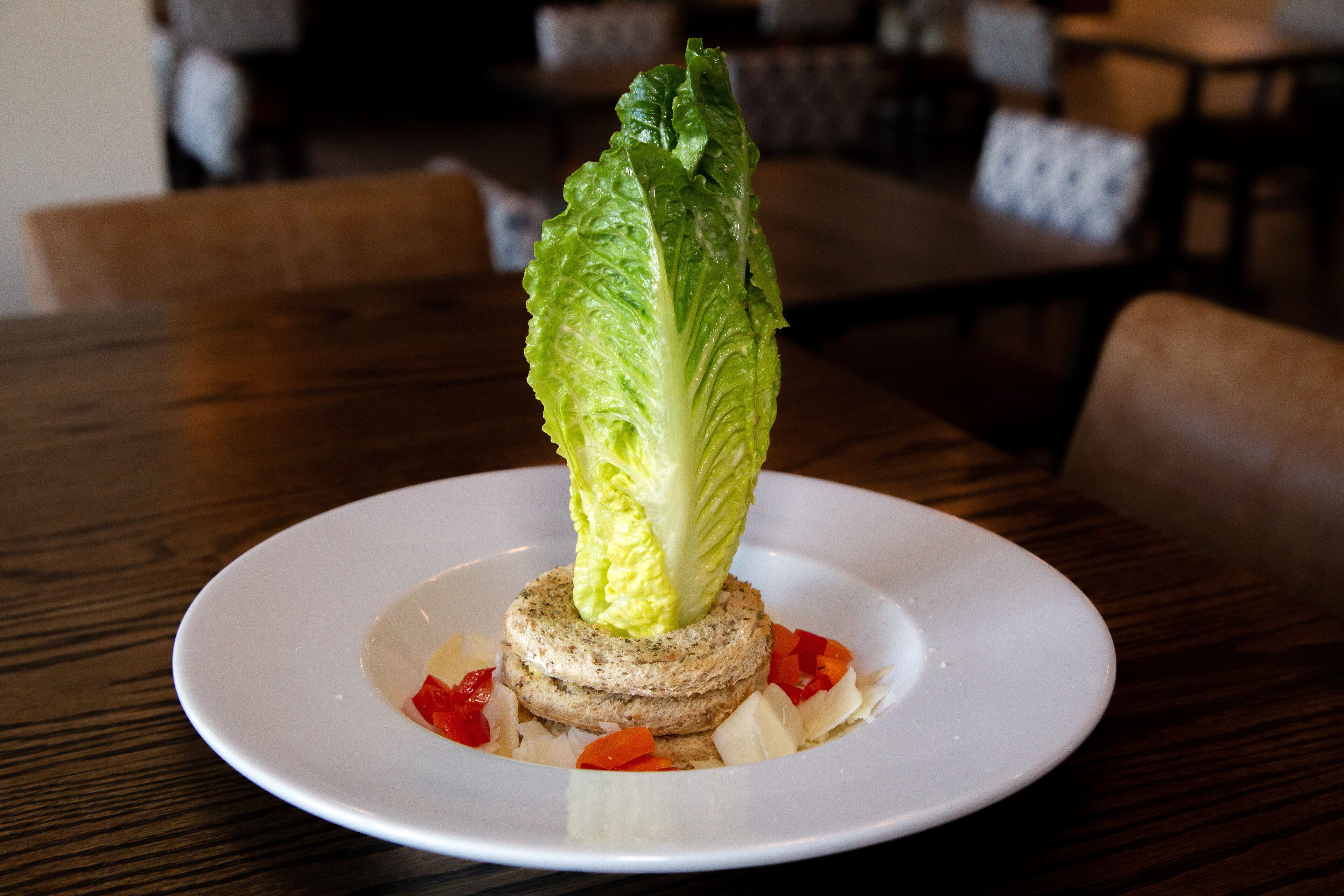 A plate with a lettuce centerpiece on a wooden table.