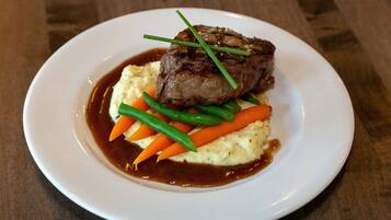 A plate with a steak, mashed potatoes, carrots, and green beans.