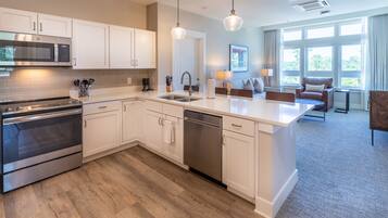 A modern kitchen with white cabinetry, stainless steel appliances, and a central island.