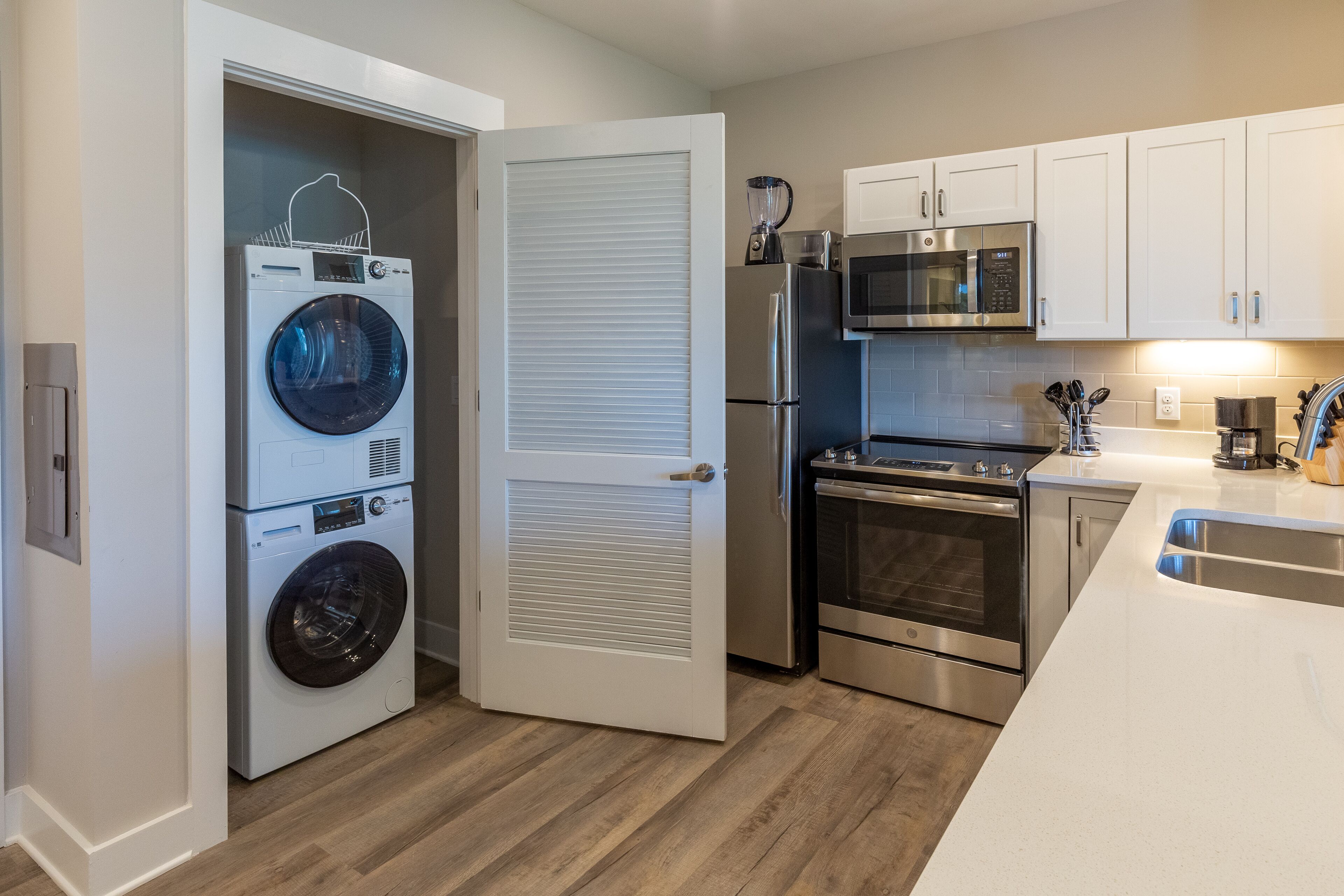 Cocina compacta con lavadora y secadora integradas, microondas, refrigerador y horno.