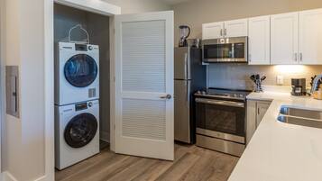 Cocina compacta con lavadora y secadora integradas, microondas, refrigerador y horno.
