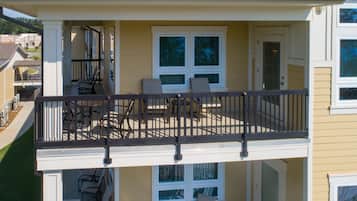 A two-story building with a balcony featuring outdoor seating and a railing.