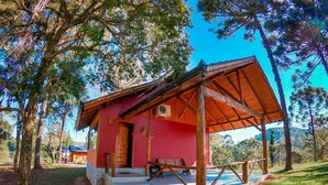 Eine kleine, rustikale Holzhütte mit roter Fassade und einer Holzterrasse.