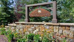 Un mur de pierres sur lequel est apposée une plaque portant l’inscription « STONEWOOD », et une variété de fleurs devant.