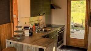 A kitchen with wooden cabinets, a central island with stools, a stove, and a sink.