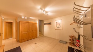 Een ruime kamer met een houten garderobe, een kapstok en een lijst met een afbeelding aan de muur.