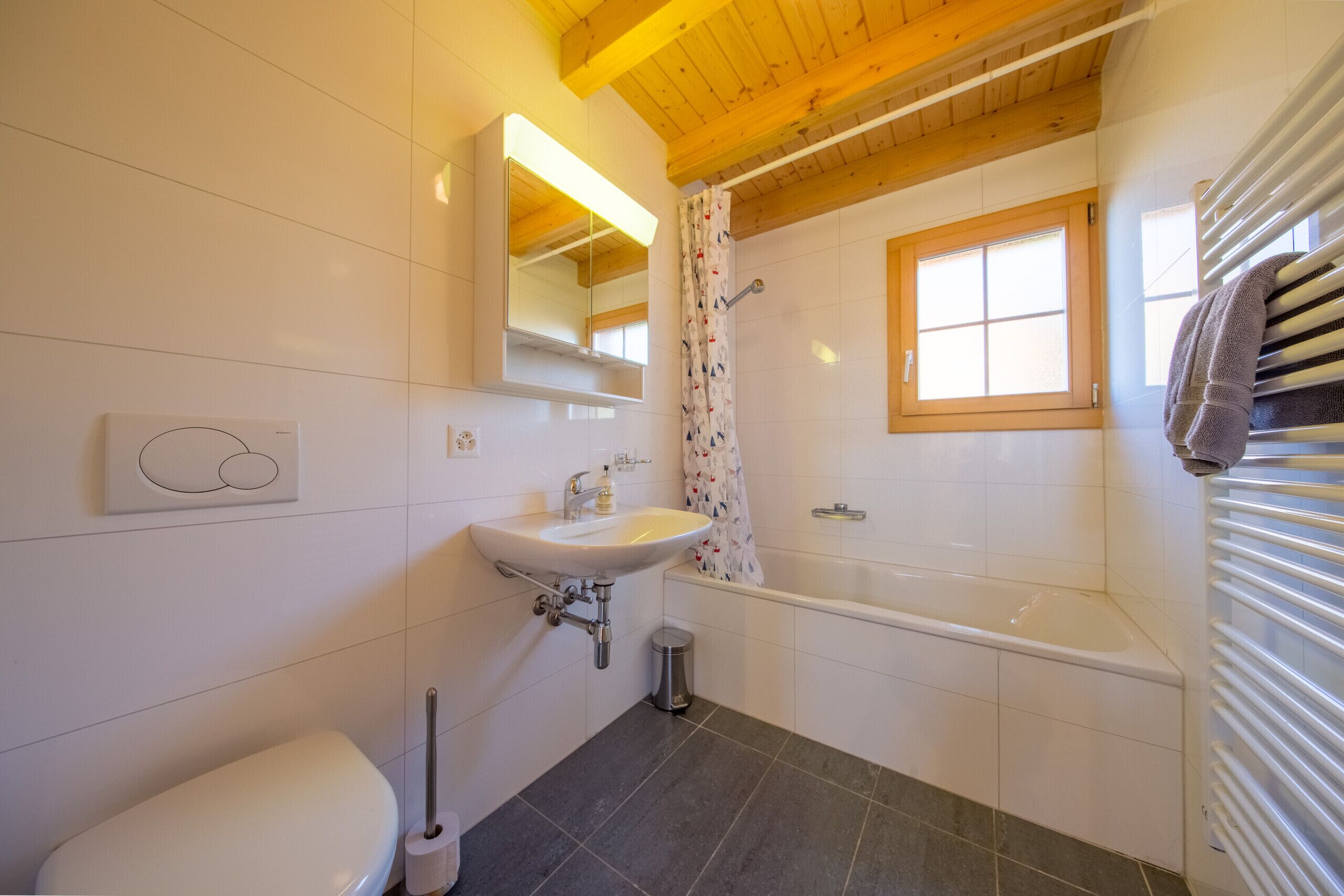 Een moderne badkamer met een witte wastafel, een toilet, een bad en een douchegordijn.
