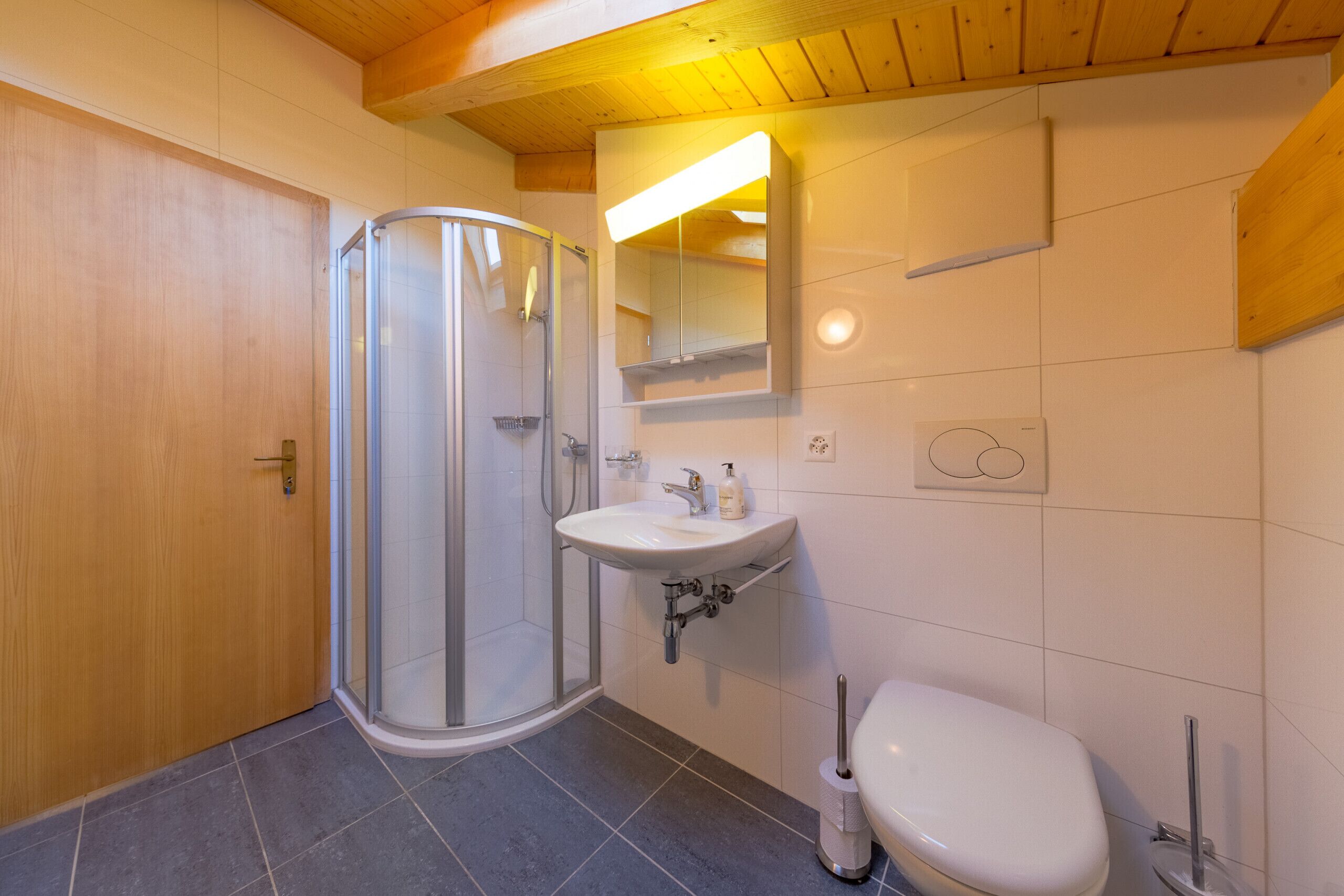 A bathroom with a glass shower enclosure, a sink, and a toilet.