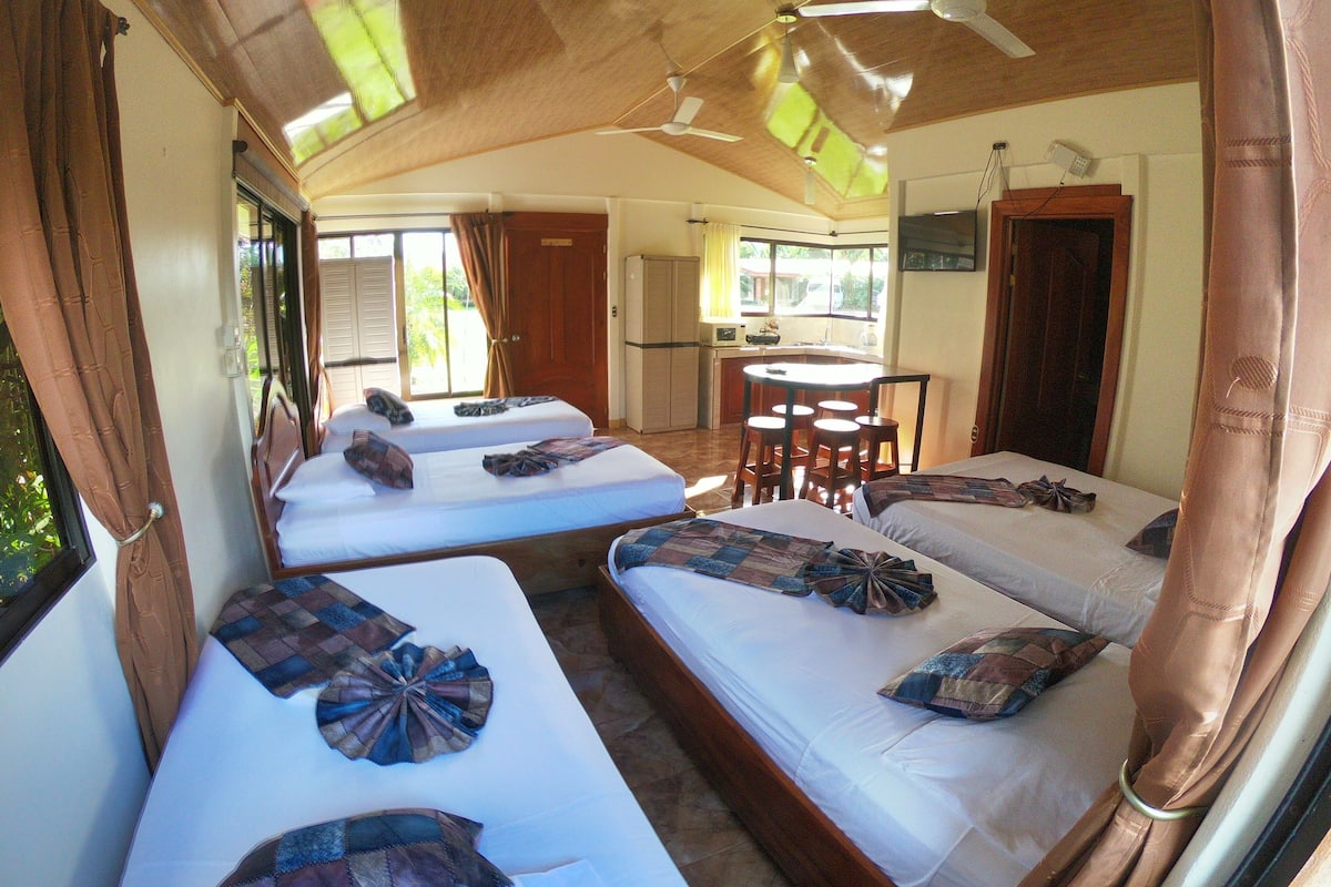 Een kamer met twee bedden, een eettafel en een keukenhoek.