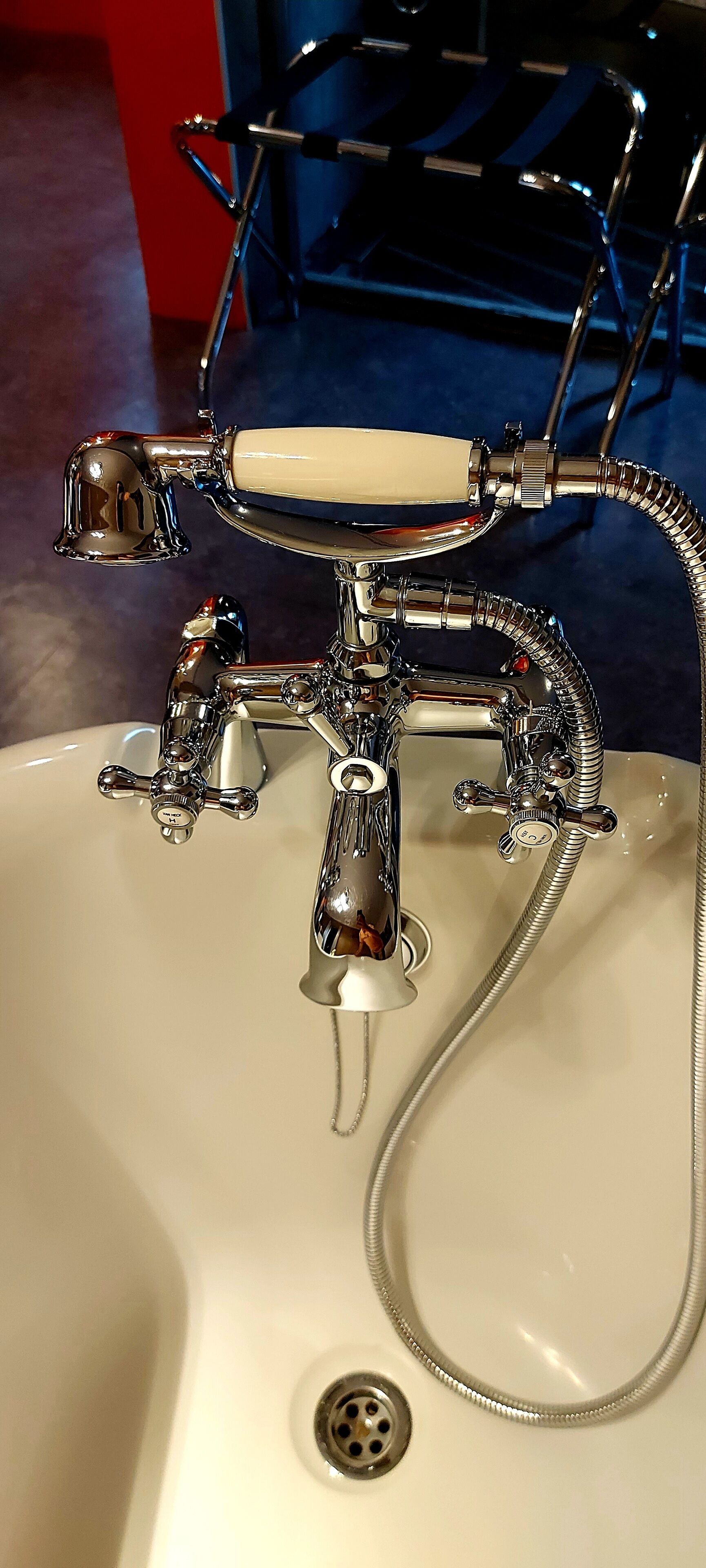 Un baño con lavamanos blanco, accesorios de cromo y un cabezal de ducha de mano.