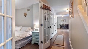 A bedroom with a bed, bedside table, and a door leading to another room.