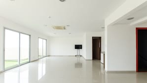 A spacious, well-lit room with large windows, a flat-screen TV, and a clean, tiled floor. - Quantum Park (Asunción)