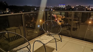 A balcony with two chairs and a table, overlooking a cityscape at night. - Quantum Park (Asunción)