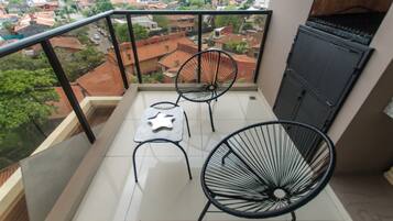 Un balcon avec deux chaises, une petite table et une vue sur le paysage urbain.