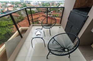 A balcony with two chairs, a small table, and a view of the cityscape. - Quantum Park (Asunción)