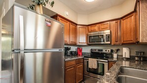 A kitchen with stainless steel appliances, wooden cabinets, granite countertops, and a built-in oven. - Updated Condo in A+ Old Town Scottsdale Location! (Scottsdale)