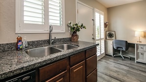 A kitchen with a granite countertop, stainless steel sink, wooden cabinets, and a built-in dishwasher. - Updated Condo in A+ Old Town Scottsdale Location! (Scottsdale)