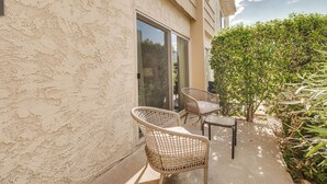 A patio with wicker chairs and a table, a sliding glass door, and a small hedge. - Updated Condo in A+ Old Town Scottsdale Location! (Scottsdale)