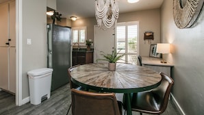 A dining area with a round wooden table, brown leather chairs, a chandelier, and a potted plant. - Updated Condo in A+ Old Town Scottsdale Location! (Scottsdale)