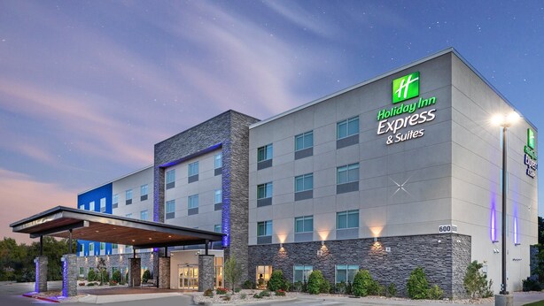 Un bâtiment de la chaîne Holiday Inn Express, doté d’un design moderne, avec une entrée abritée et une façade bien éclairée.