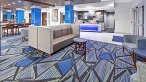 Un hall d’hôtel comprenant un comptoir d’accueil, un espace salon et un tapis à motifs.
