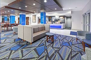 A hotel lobby with a reception desk, seating area, and a patterned carpet.