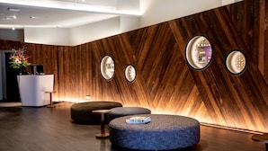 Een moderne lobby met houten lambrisering, ronde wandlampen en een receptiebalie.